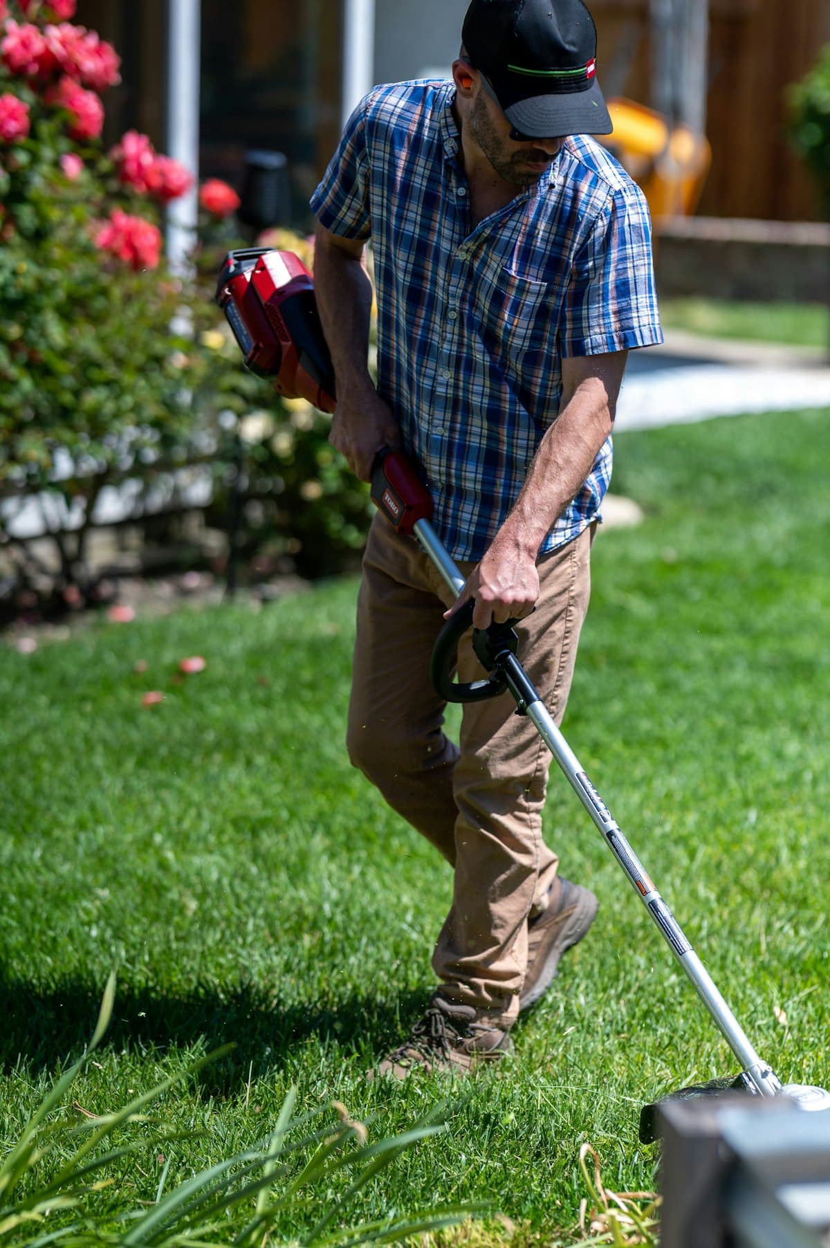 A landscaper trimming a customer's lawn on a sunny afternoon